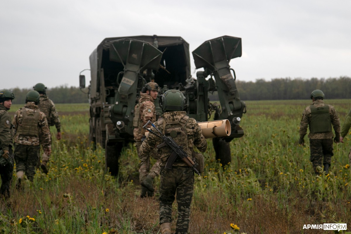 M1083 MTV cargo (Oshkosh-built) — 406th Artillery Brigade showing their M777 howitzers and iconic B-kit FMTV M1083 with Cheshire Cat smile and eyes painted
